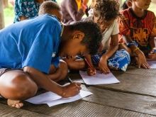 A boy writing whilst leaning on the floor