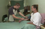 Male nurse takes blood pressure of male patient sitting in bed
